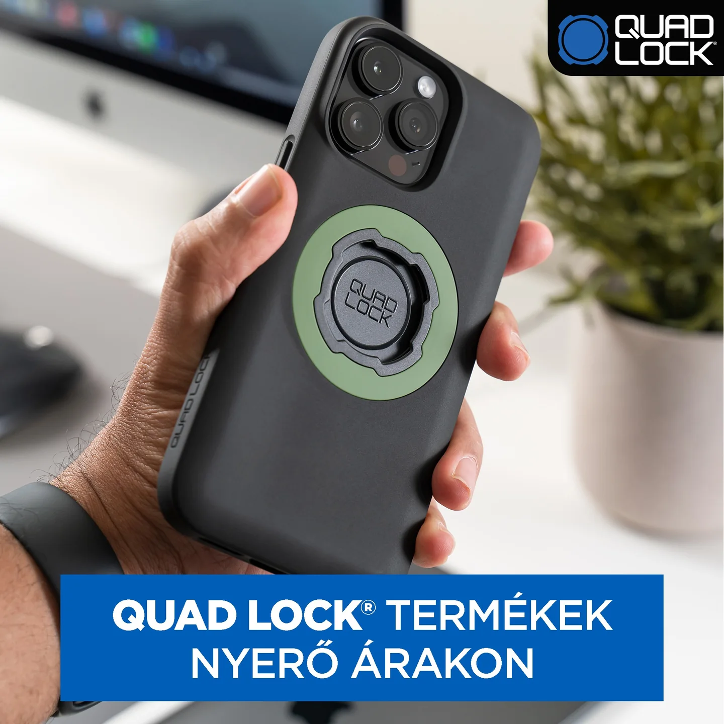 MOTOBOX ad showing a Quad Lock phone case with a green MAG ring in an office setting, with a blue panel advertising Quad Lock products at winning prices.